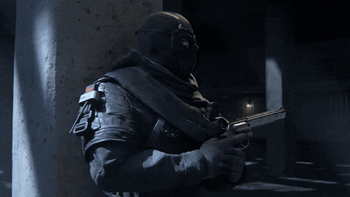 A Man In A Mask Is Holding A Gun With The Letter T On The Barrel GIF