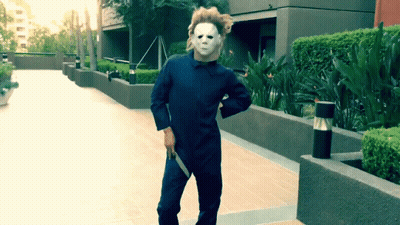 A Man In A Mask Is Holding A Knife In His Hand GIF