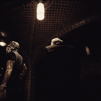 A Man In A Mask Is Standing In A Dark Hallway GIF