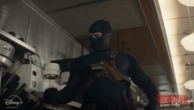 A Man In A Mask Is Standing In A Room With A Disney + Logo GIF