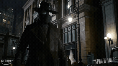 A Man In A Mask Is Standing In Front Of A Building That Says Spider-Man On It GIF