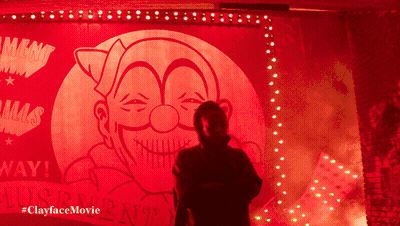 A Man In A Mask Is Standing In Front Of A Sign That Says ' Lust ' On It GIF