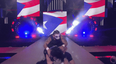 A Man In A Mask Is Wrestling Another Man In Front Of An American Flag GIF