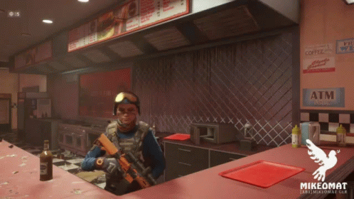 A Man In A Mask Stands At A Counter In A Restaurant With A Sign That Says Atm Inside GIF