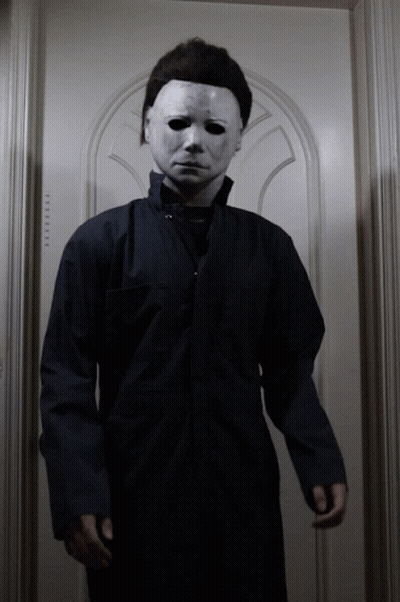 A Man In A Mask Stands In Front Of A Door That Says ' Elevator ' GIF