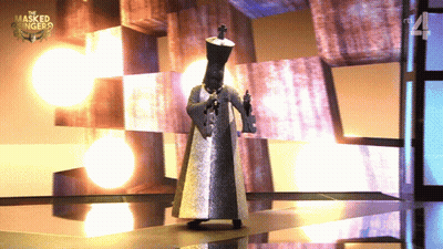 A Man In A Masked Singer Costume Is Standing On A Stage GIF