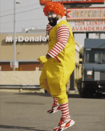 A Man In A Mcdonald 'S Costume Is Jumping In Front Of A Mcdonald 'S GIF