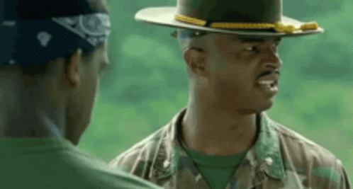 A Man In A Military Uniform And Hat Is Talking To Another Man . GIF
