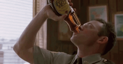 A Man In A Military Uniform Is Drinking A Bottle Of Beer . GIF