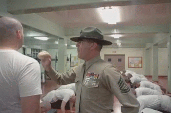 A Man In A Military Uniform Is Giving A Fist Bump To A Man In A White Shirt . GIF