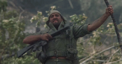 A Man In A Military Uniform Is Holding A Rifle With His Arms Outstretched GIF