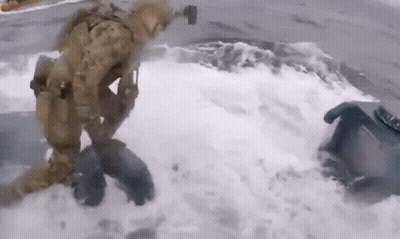 A Man In A Military Uniform Is Kneeling In The Water . GIF