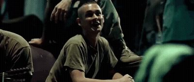 A Man In A Military Uniform Is Laughing While Sitting On The Ground . GIF