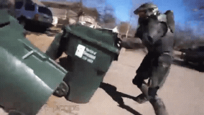 A Man In A Military Uniform Is Pushing A Trash Can Down A Street . GIF