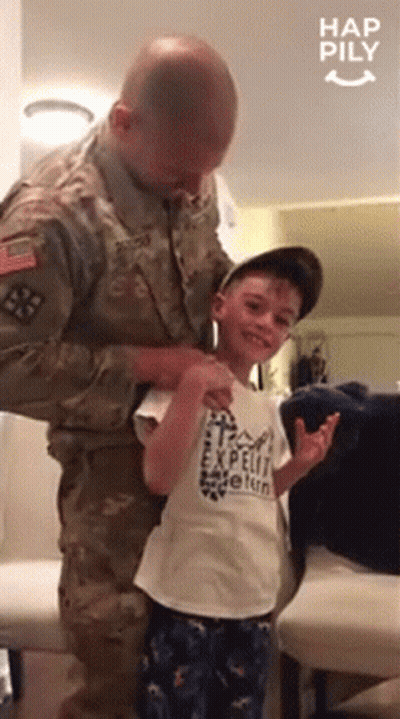 A Man In A Military Uniform Is Putting A Shirt On A Young Boy Who Is Wearing A Shirt That Says Expedit Vetern GIF