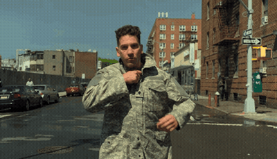 A Man In A Military Uniform Is Running Down A Street With A One Way Sign In The Background GIF
