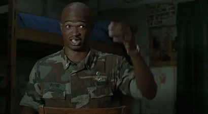 A Man In A Military Uniform Is Sitting In A Chair And Pointing At Something . GIF