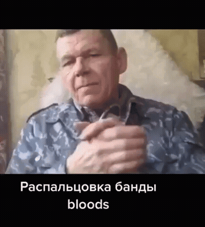 A Man In A Military Uniform Is Sitting In A Chair With His Hands Folded In Front Of Him . GIF