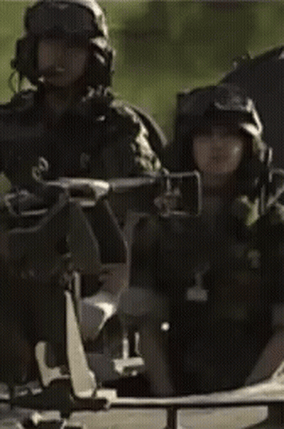 A Man In A Military Uniform Is Sitting In A Vehicle With Other Soldiers . GIF