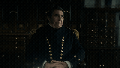 A Man In A Military Uniform Is Sitting In Front Of A Sign That Says That Is An Interesting Speculation GIF
