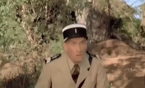A Man In A Military Uniform Is Sitting In The Woods . GIF