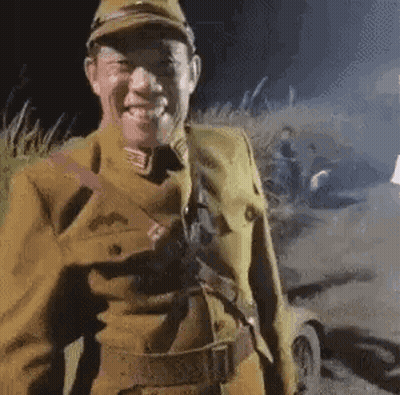 a man in a military uniform is smiling while standing in a field .