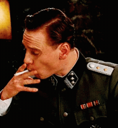 A Man In A Military Uniform Is Smoking A Cigarette While Wearing A Medal GIF