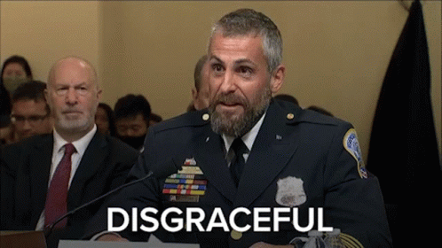 A Man In A Military Uniform Is Speaking Into A Microphone With The Word Disgraceful Written Below Him GIF
