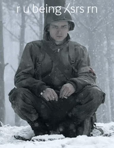 A Man In A Military Uniform Is Squatting In The Snow GIF
