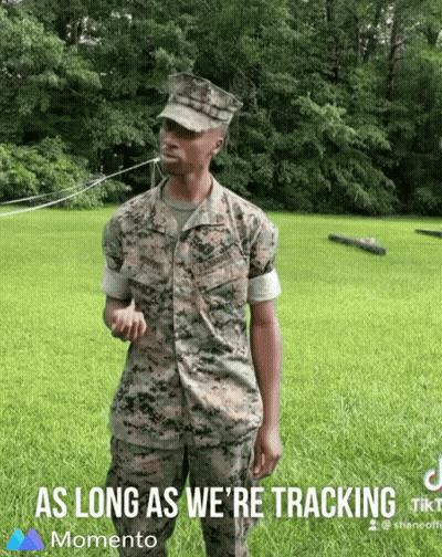 A Man In A Military Uniform Is Standing In A Grassy Field With The Words " As Long As We 'Re Tracking " Below Him GIF