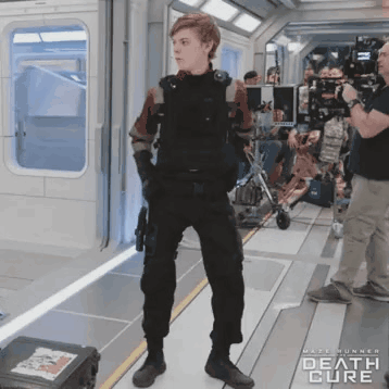 A Man In A Military Uniform Is Standing In A Room With The Words Death Cure On The Bottom GIF