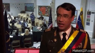 A Man In A Military Uniform Is Standing In Front Of A Group Of People In A Room . GIF