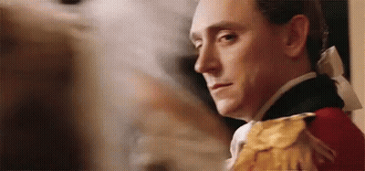 A Man In A Military Uniform Is Standing In Front Of A Painting And Looking At The Camera . GIF