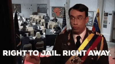 A Man In A Military Uniform Is Standing In Front Of A Room With People Sitting At Desks . GIF