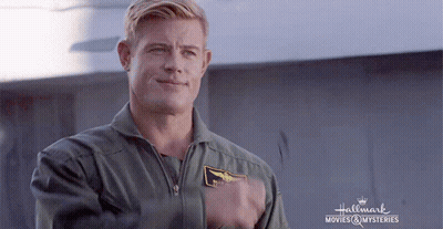 A Man In A Military Uniform Is Standing In Front Of A Sign That Says Hallmark Movies & Mysteries . GIF