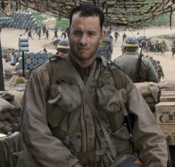A Man In A Military Uniform Is Standing In Front Of A Stack Of Boxes That Say Fire GIF