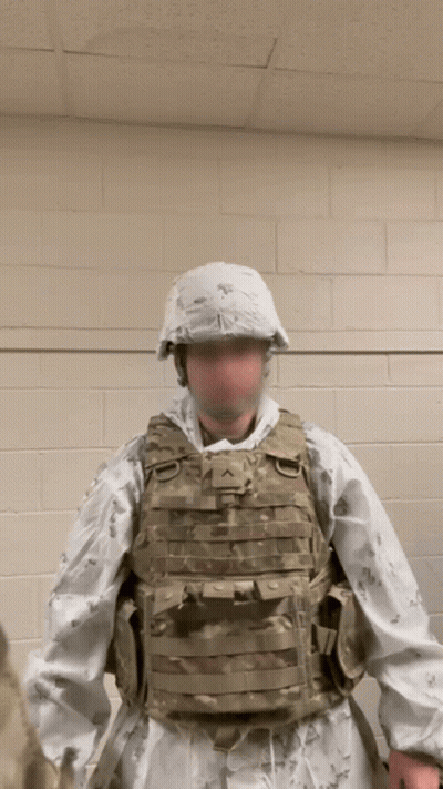 A Man In A Military Uniform Is Standing In Front Of A White Wall GIF