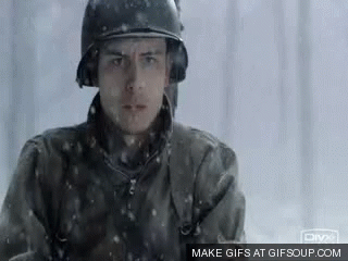 A Man In A Military Uniform Is Standing In The Snow . GIF