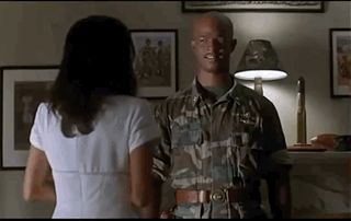 A Man In A Military Uniform Is Standing Next To A Woman In A White Dress In A Living Room . GIF