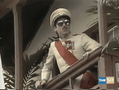 A Man In A Military Uniform Is Standing On A Balcony With A Sign That Says Tvm 50 On It GIF