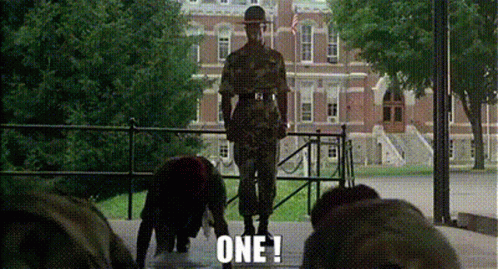 A Man In A Military Uniform Is Standing On A Stage In Front Of A Building With The Words `` One ! '' GIF