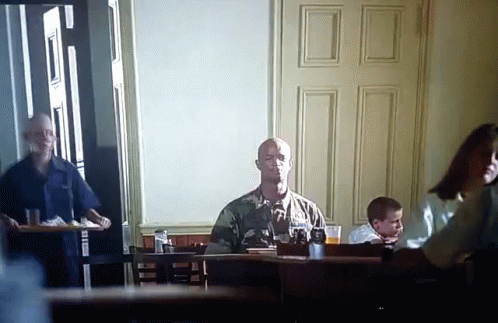 A Man In A Military Uniform Sits At A Table With A Glass Of Beer GIF