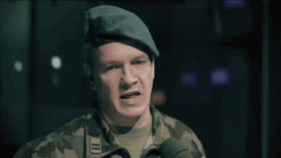 A Man In A Military Uniform Speaking Into A Microphone With The Word Sur In The Background GIF