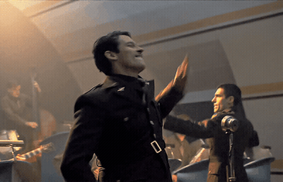 A Man In A Military Uniform Stands In Front Of A Band GIF