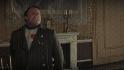 A Man In A Military Uniform Stands In Front Of A Fireplace And A Clock GIF