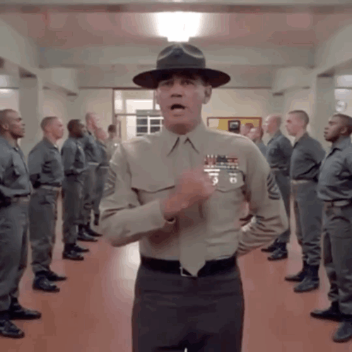 A Man In A Military Uniform Stands In Front Of A Group Of Men GIF