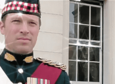 A Man In A Military Uniform Stands In Front Of A White Building GIF