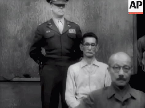 A Man In A Military Uniform Stands Next To A Man In A White Shirt With Glasses GIF