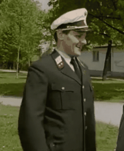 A Man In A Military Uniform With A White Hat Is Smiling . GIF