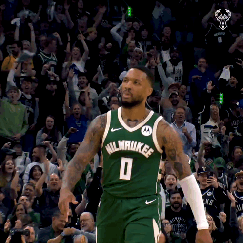 A Man In A Milwaukee Jersey Stands In Front Of A Crowd Of People GIF